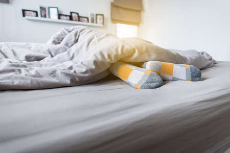 Foot with sock and feet on the bed after waking upの写真素材