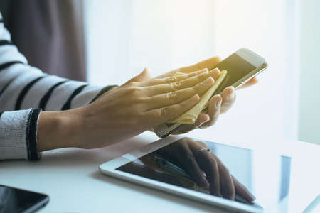 Hand woman cleaning smart phone on screen with microfiber clothの写真素材
