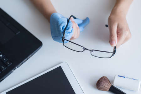 Hand woman cleaning her glasses with cloth,Clean lenses of eyeglassesの写真素材