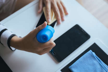 Hand female cleaning dirty smart phone on screen with microfiber clothの写真素材