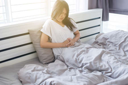 Asian woman having painful stomachache,Female suffering from abdominal pain,Period crampsの写真素材