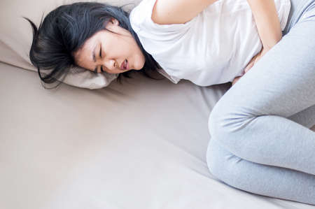 Asian woman having painful stomachache,Female suffering from abdominal pain,Period crampsの写真素材