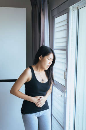 Asian woman having painful stomachache,Female suffering from abdominal pain,Period cramps