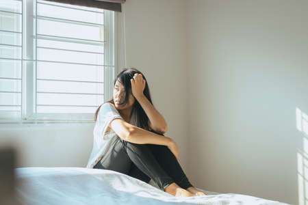 Woman have a headache and feeling sadness on bed after wake up in the morningの写真素材