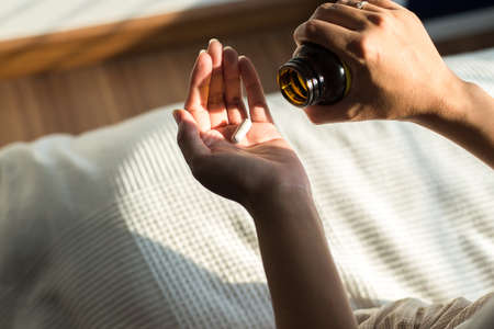 Woman hands with pills on spilling pills out of bottle. Female hand holding a medicineの写真素材