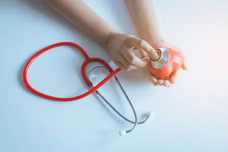 Woman doctor hands holding stethoscope to checking red heart from patient,Health care checking concept,Selective focusの写真素材