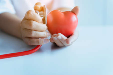 Woman doctor hands holding stethoscope to checking red heart from patient,Health care checking concept,Selective focusの写真素材