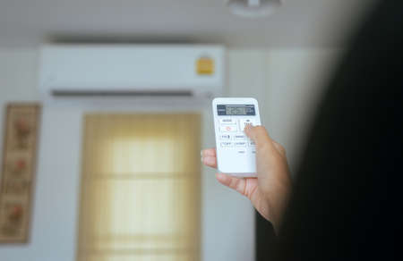 Hand using a remote control to activating temperature air conditioning の写真素材