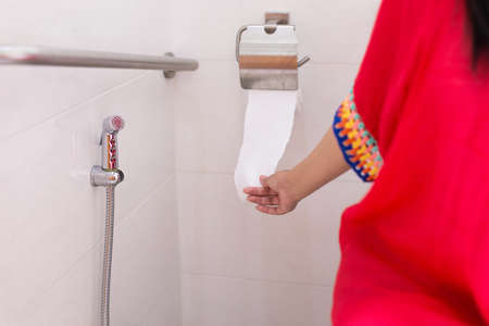 Woman holding toilet paper and using toilet in morning