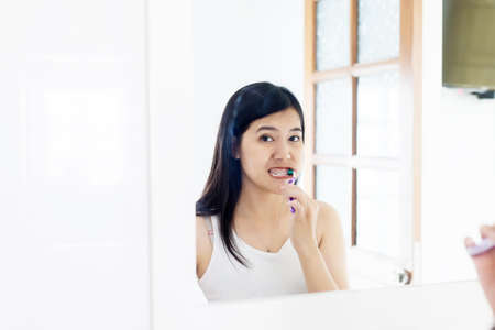 Young asian woman brush the teeth in bathroom after wake up in morningの写真素材