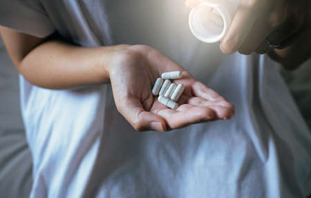 Woman hands with pills on spilling pills out of bottle,Female hand holding a medicine