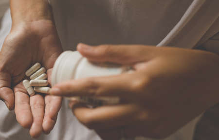 Woman hands with pills on spilling pills out of bottle,Female hand holding a medicine,Selective...