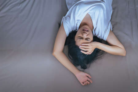 Asian woman have a headache on bed after wake up in the morning