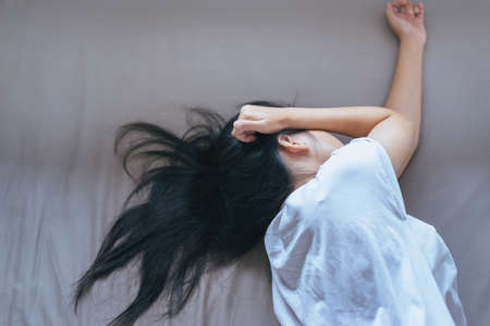 Asian woman have a headache,stressed and exhausted on bed after wake up in the morning