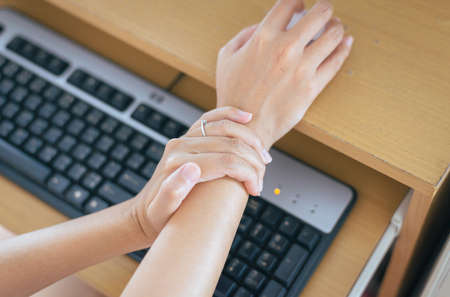 Woman having a wrist or hand pain,Female feeling exhausted and painful,Because clicking the mouse and using computerの写真素材