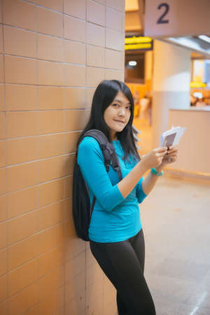 Beautiful asian woman passenger holding passport and checking flight or online check in and travel planner at international airportの写真素材