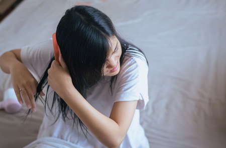 Young asian woman after bath hairbrushing her hair with combの写真素材