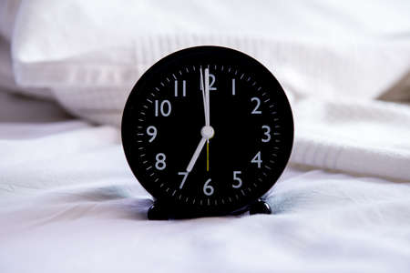 Close up of black alarm clock on the white bedの写真素材