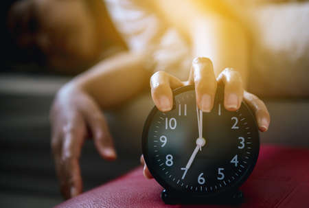 Hand hates getting stressed waking up early,Female stretching her hand to ringing alarm to turn off alarm clockの写真素材