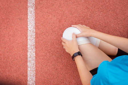 Woman suffering from pain in leg injury after running,Female runner using elastic bandage with leg,Female putting bandage on her injured kneeの写真素材