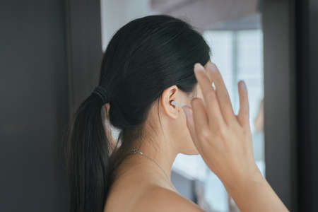 Woman cleaning her ears with cotton bud in bedroom,Female using cotton stick