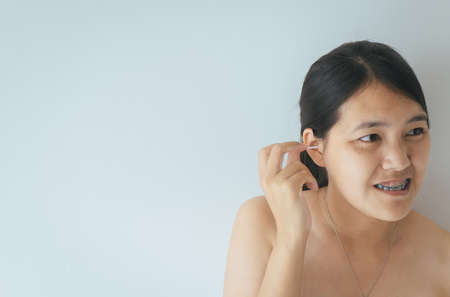 Woman cleaning her ears with cotton bud in bedroom,Female using cotton stick.Selective focusの写真素材