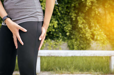 Hand touching her muscle thigh after jogging on road,Woman runner suffering from pain in legs be injuredの写真素材