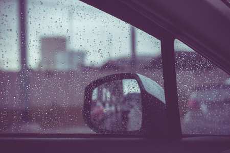 Car window with rain drops on glass or the windshield,Blurred traffic on rainy day in the city,Vintage tonedの写真素材
