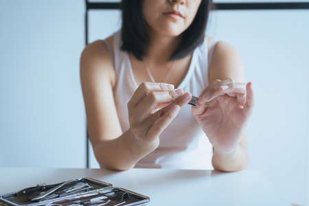 Woman cutting nails with nail clipper,Female using tweezers clipping hes fingernailsの写真素材