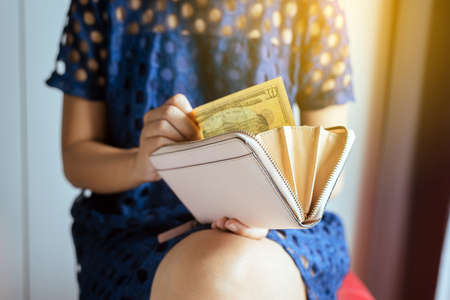 Hands woman counting US dollar bills into walletの写真素材