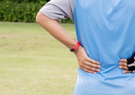 Man suffering from pain in his back injury after sport exercise running jogging and workout outdoorの写真素材