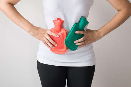 Stomachache,Abdominal surface,Woman hand using 2 hot water bag or bottle on her belly on bedroom