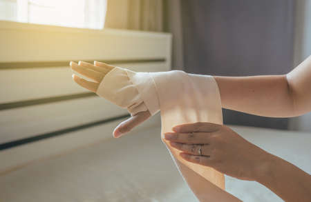 Woman using elastic bandage with hand,Female putting bandage on his injured handsの写真素材