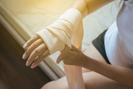 Woman using elastic bandage with hand,Female putting bandage on his injured handsの写真素材