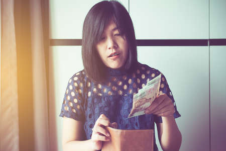 Hands woman counting 1000 Thai baht banknote bills into walletの写真素材