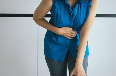 Woman having painful stomachache and gastritis,Hand squeezing her bellyの写真素材