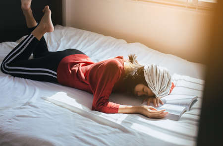 Asian woman reading a book laying down and be serious on bedroomの写真素材
