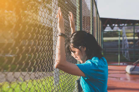 Tired woman runner running outdoor and jogging in sunrise lightの写真素材