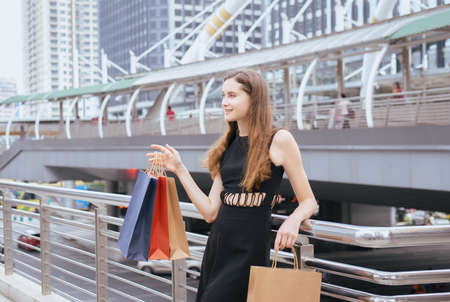 Portrait of beautiful young girl smling and holding shopping bags in city,Woman looking with relaxed expression,Lifestyle conceptの写真素材