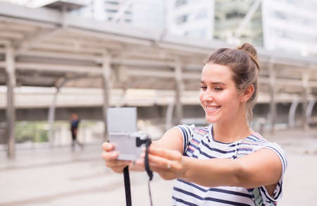 Happy and smiling female traveler is making her selfie in the city,Beautiful girl walking on the...