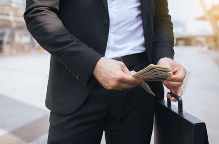 Business man in suit holding US dollar bills and counting money,Close upの写真素材