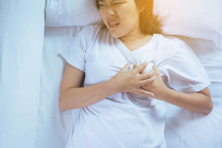 Woman with strong chest pain and hands touching her chest,Heart attack symptom