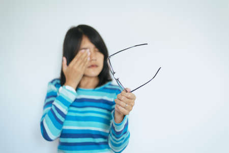 Blur of woman suffering from eyes pain hands holding eyeglasses and rubs her nose eye out of tiredの写真素材
