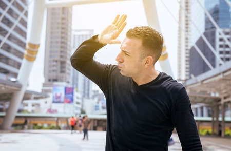 Men raise hand to cover his face from sunlight on street