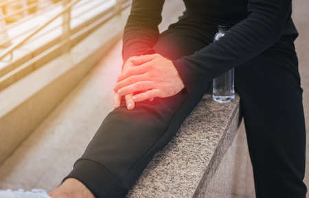 Man with pain in the legs and hand touching his knee painfulの写真素材