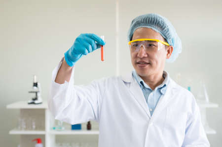 Scientist hands holding medical chemicals sample in test tube with blood sampleの写真素材