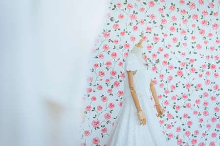 Modern white wedding dress on a mannequin with blured flower backgroundの写真素材