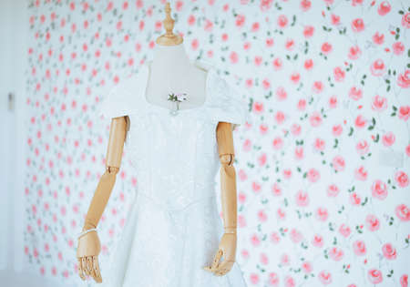 Modern white wedding dress on a mannequin with blured flower backgroundの写真素材