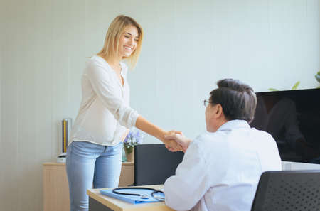 Happy and smiling woman patient giving handshake to man doctor at the hospital,Thank you