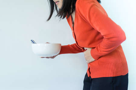 Digestion problems,Woman with stomach pain after eating,Hand female holding her bellyの写真素材